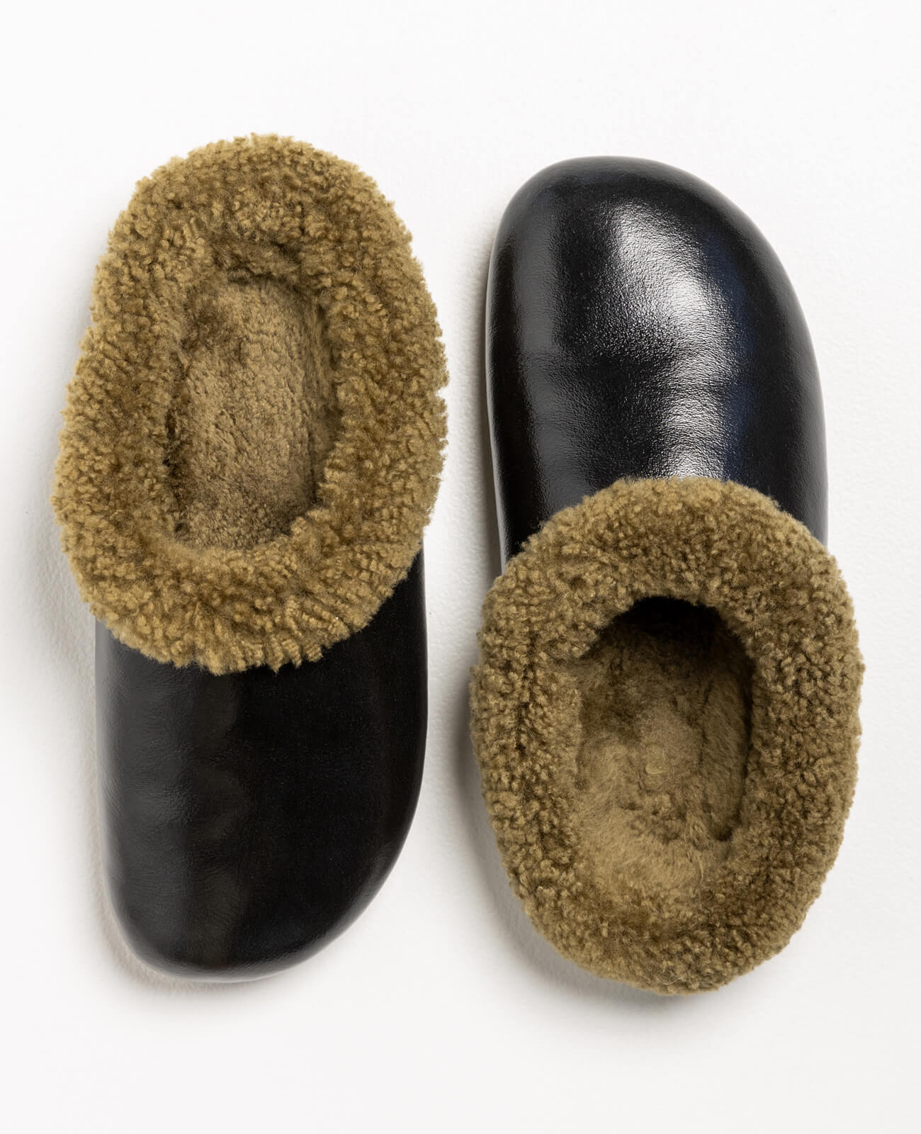 Pantoffel Muti slippers in black leather with a rich brown sheepskin lining, blending sophistication with cozy warmth.