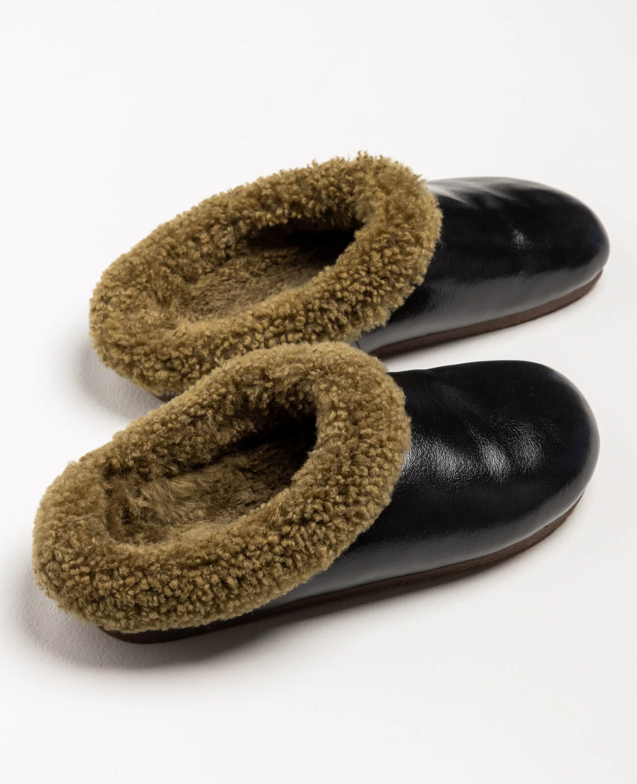 Pantoffel Muti slippers in black leather with a rich brown sheepskin lining, blending sophistication with cozy warmth.