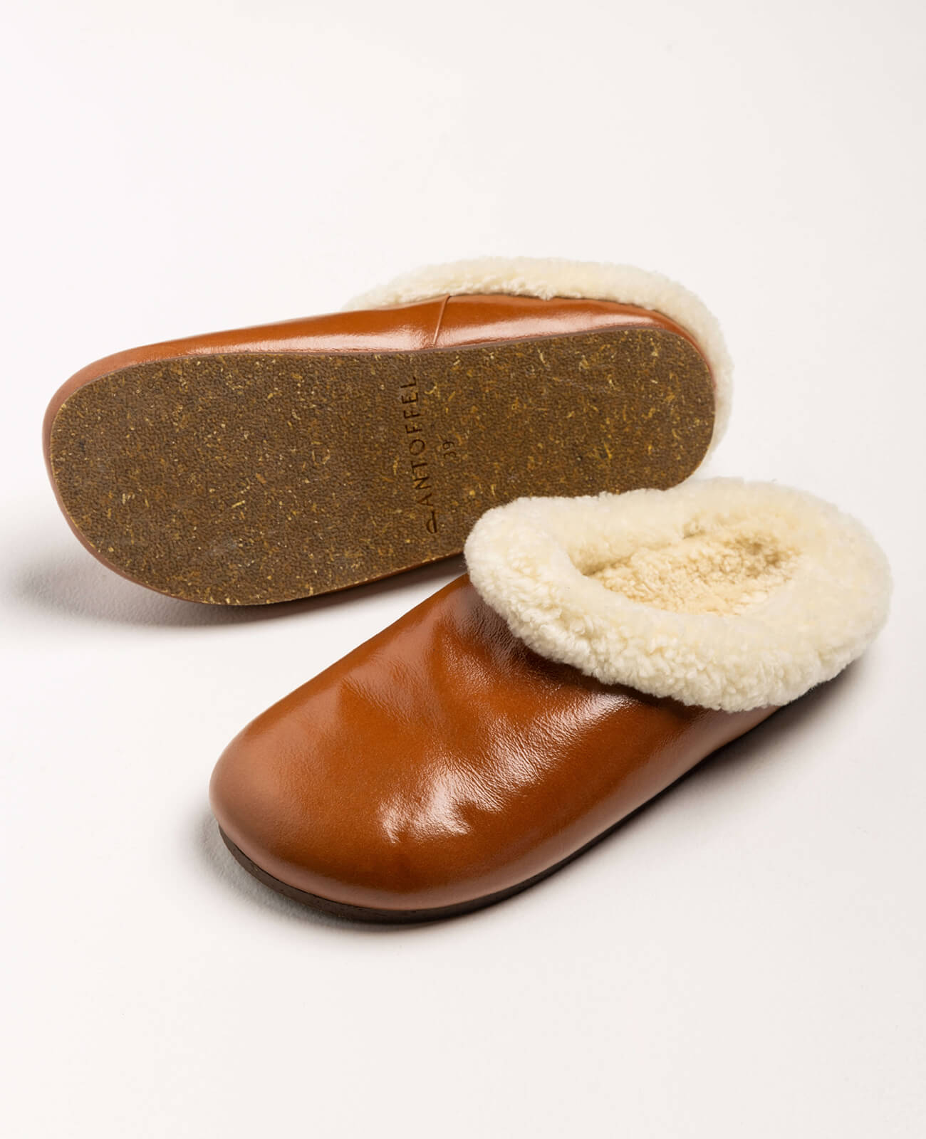 Pantoffel Muti slippers in rust-colored leather with a plush cream sheepskin lining, designed for comfort and luxury.