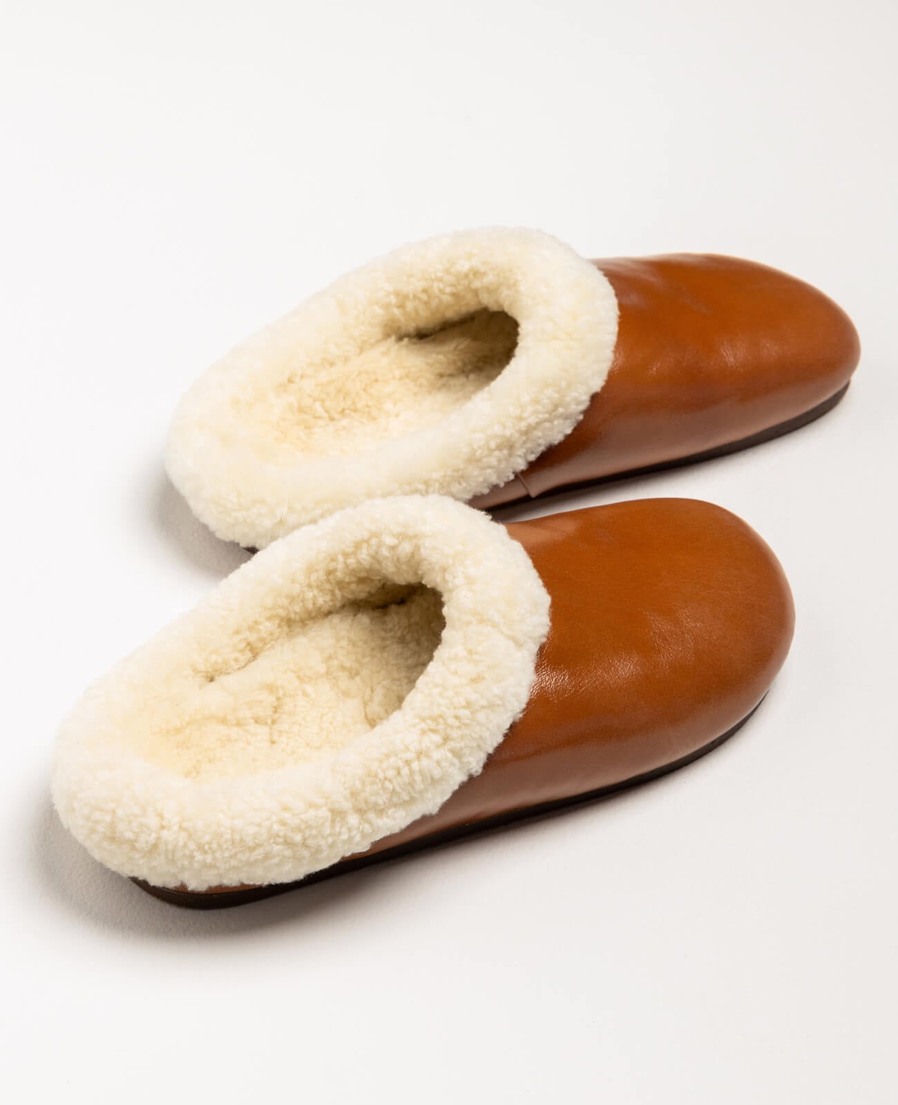 Pantoffel Muti slippers in rust-colored leather with a plush cream sheepskin lining, designed for comfort and luxury.