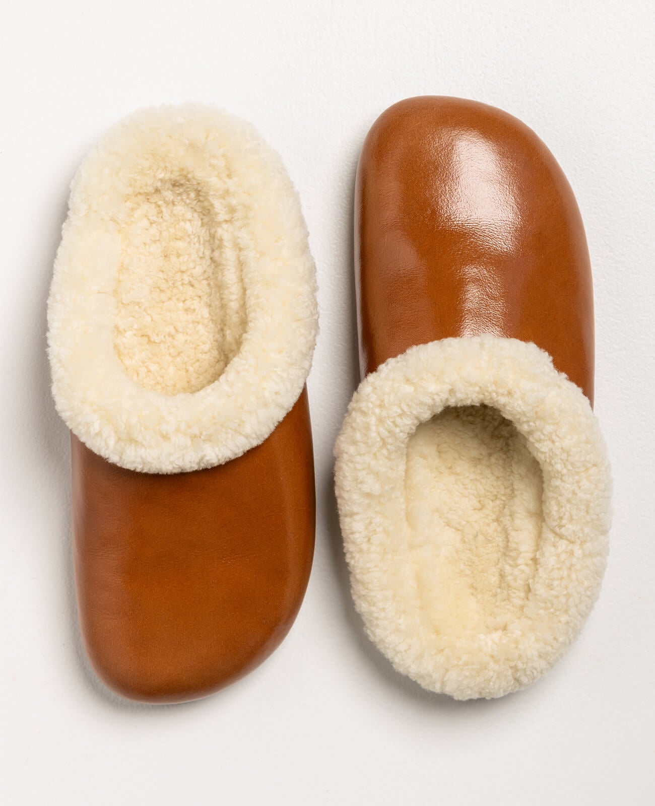 Pantoffel Muti slippers in rust-colored leather with a plush cream sheepskin lining, designed for comfort and luxury.